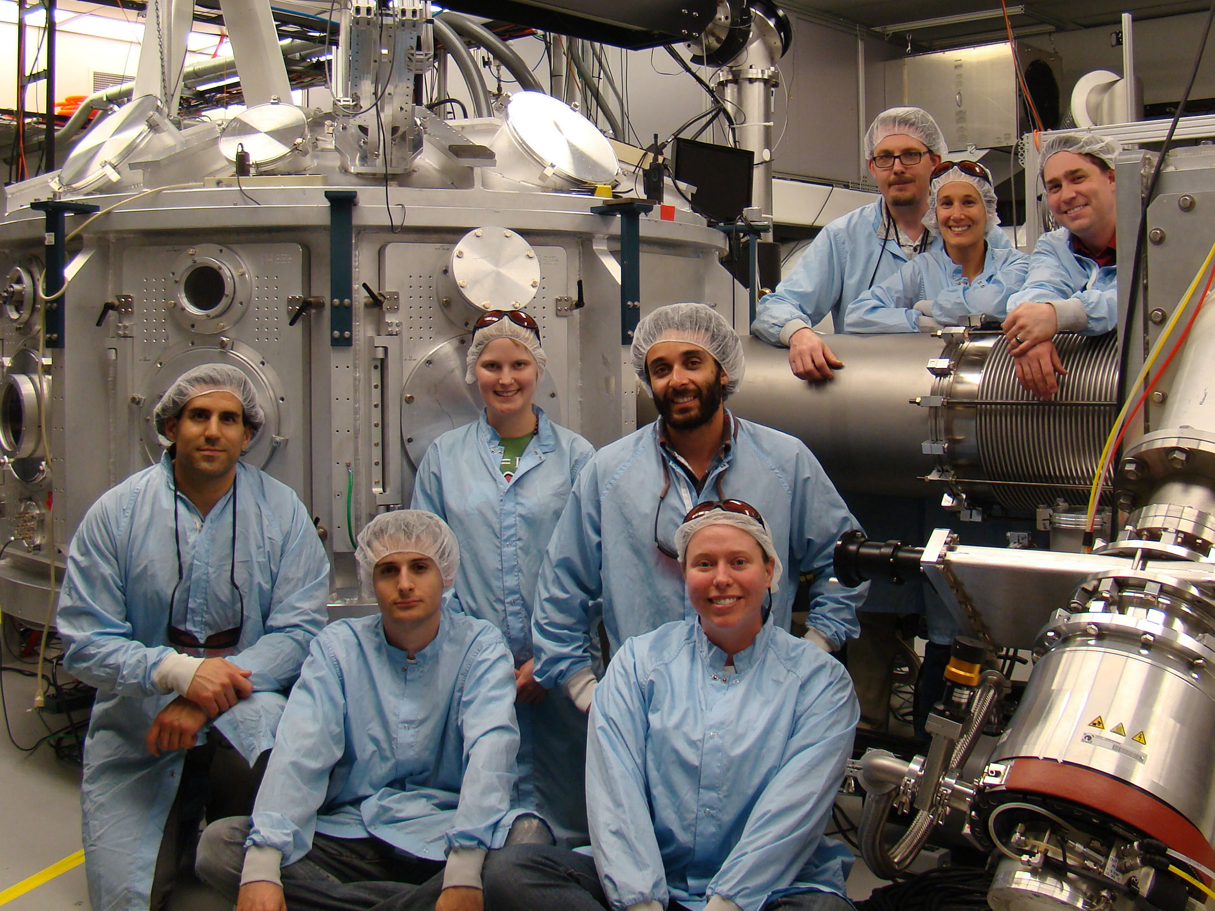 Group of lab-workers in front of lab equipment.